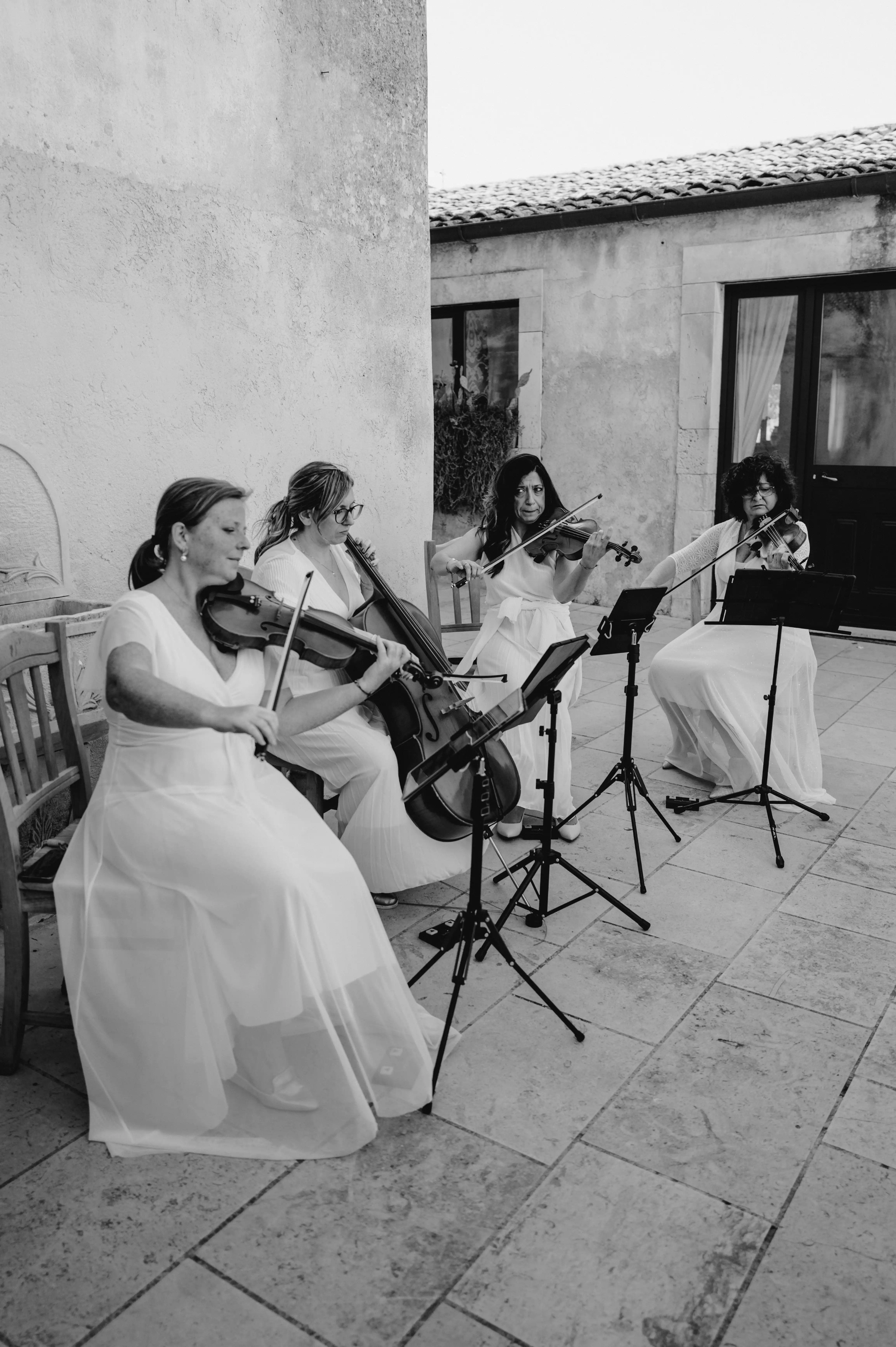 String quartet performing live music during an elegant outdoor wedding reception in Sicily.